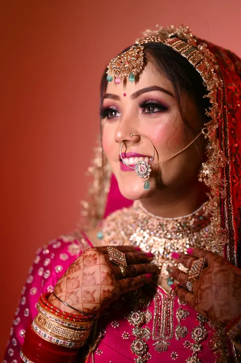 A bride in pink smiling, wearing a nath
