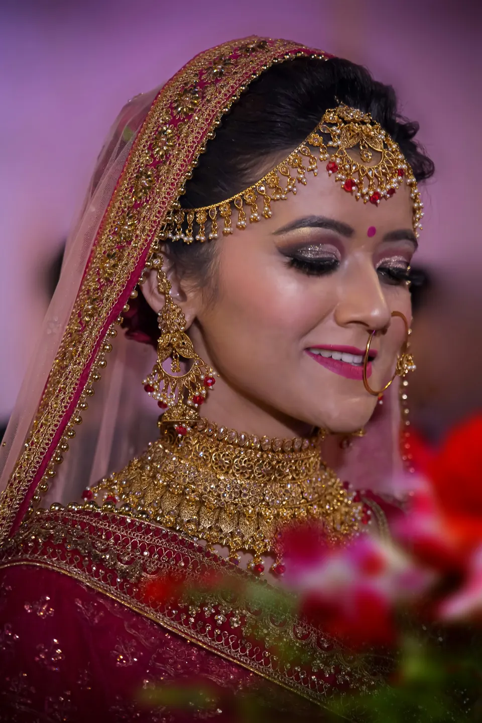 A bride in red with a veil and gold jewellery