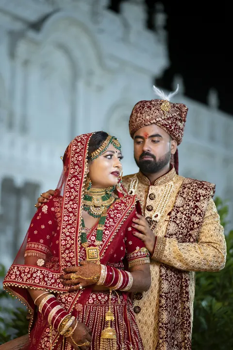 A couple in wedding clothes outside a white building