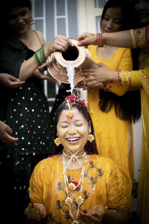 Relatives pouring water from a brass pot over a bride