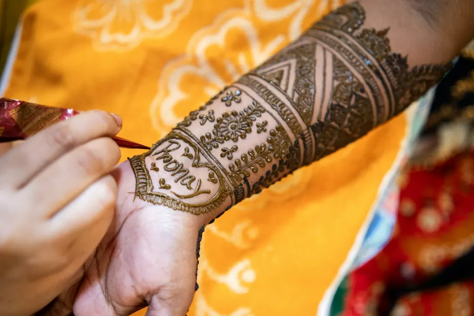 An artist drawing a henna pattern on a bride's arm