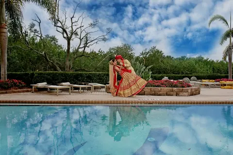 A woman in a pink outfit seated by a pool