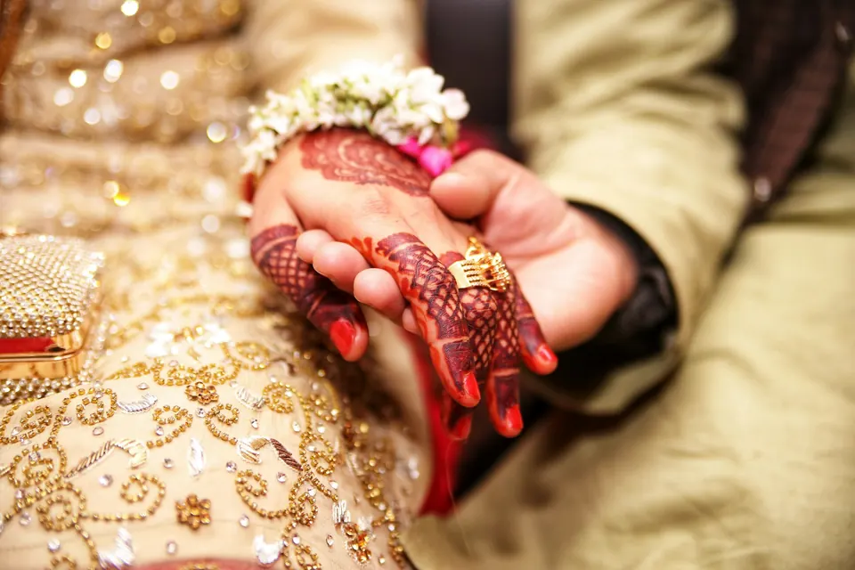 Close-up of hands exchanging a ring over an embroidered outfit