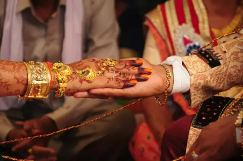 A man holding a red and gold sehra